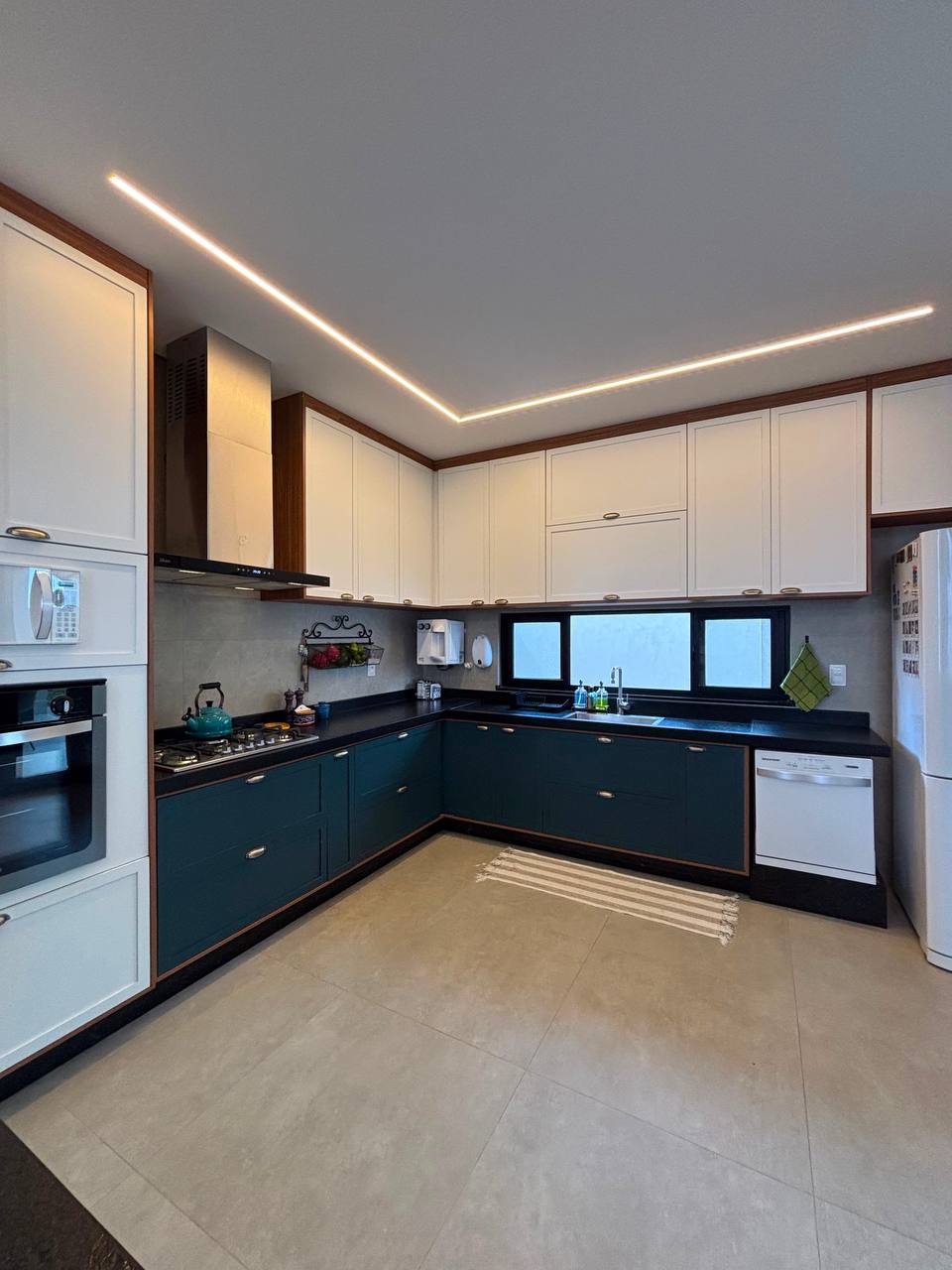 Cozinha planejada com armários em L, bancada escura e iluminação linear
