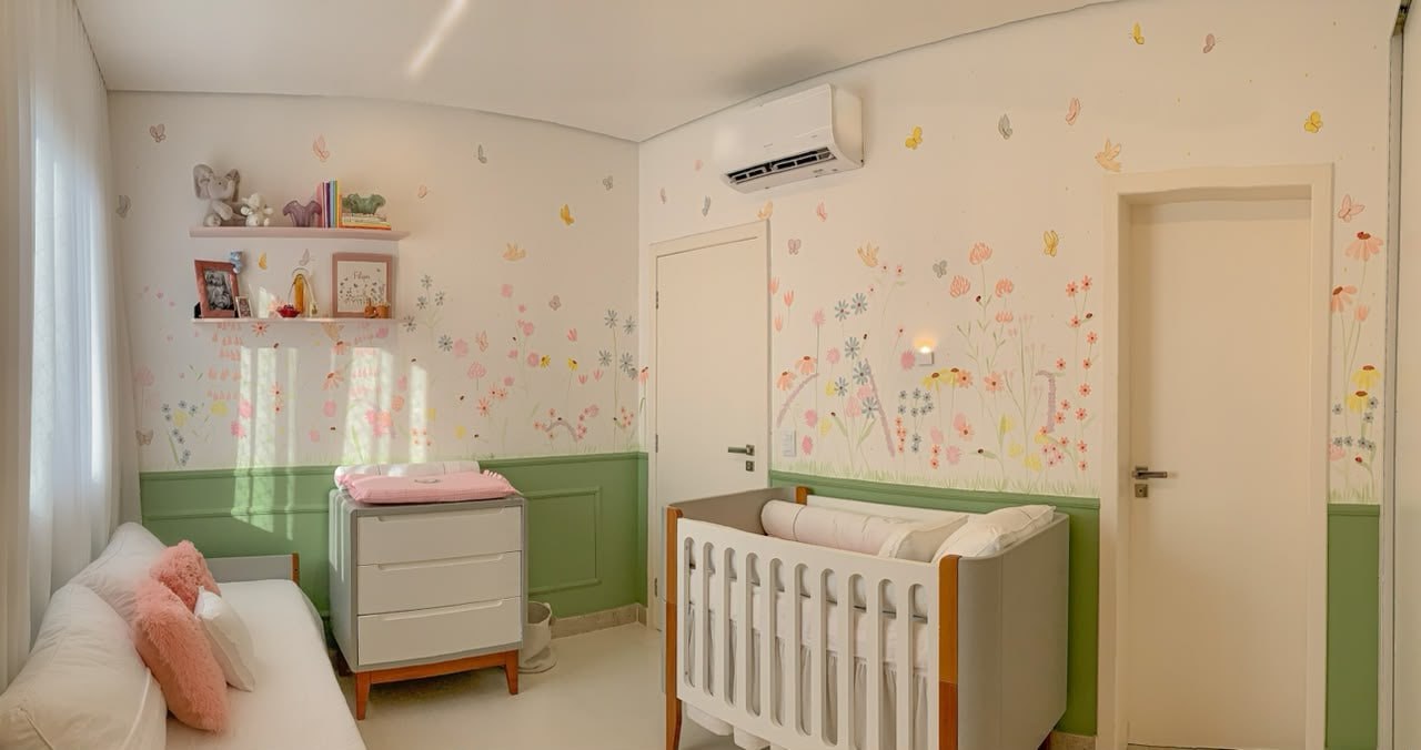 Espaço infantil delicado com berço, boiserie verde e papel de parede floral