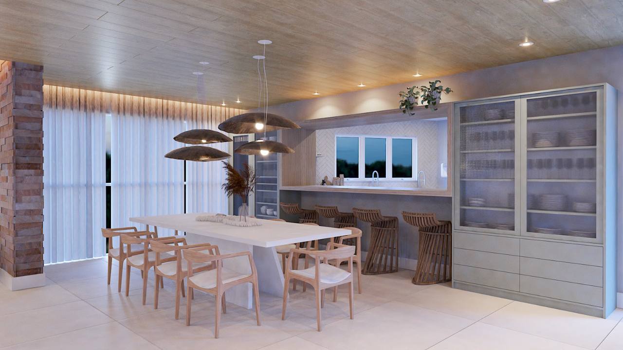 Sala de jantar integrada com mesa ampla, pendentes e área gourmet ao fundo